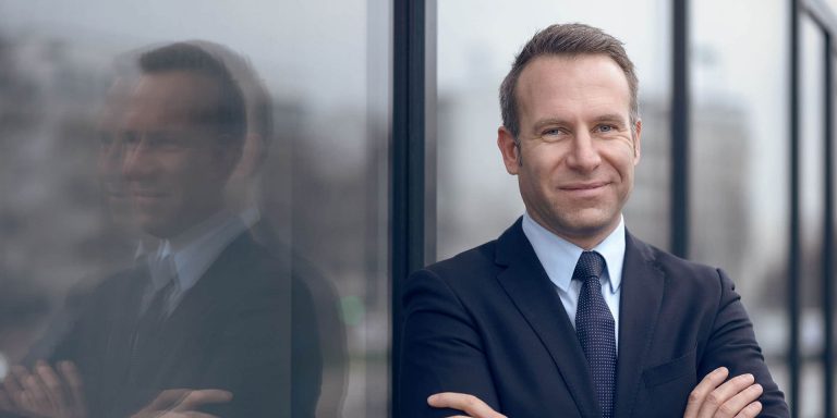 confident man folding both hands and standing by wall